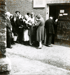 876759 Afbeelding van een rij wachtenden met emmers en pannen bij de voedseluitdeling uit de gaarkeuken gerund door de ...